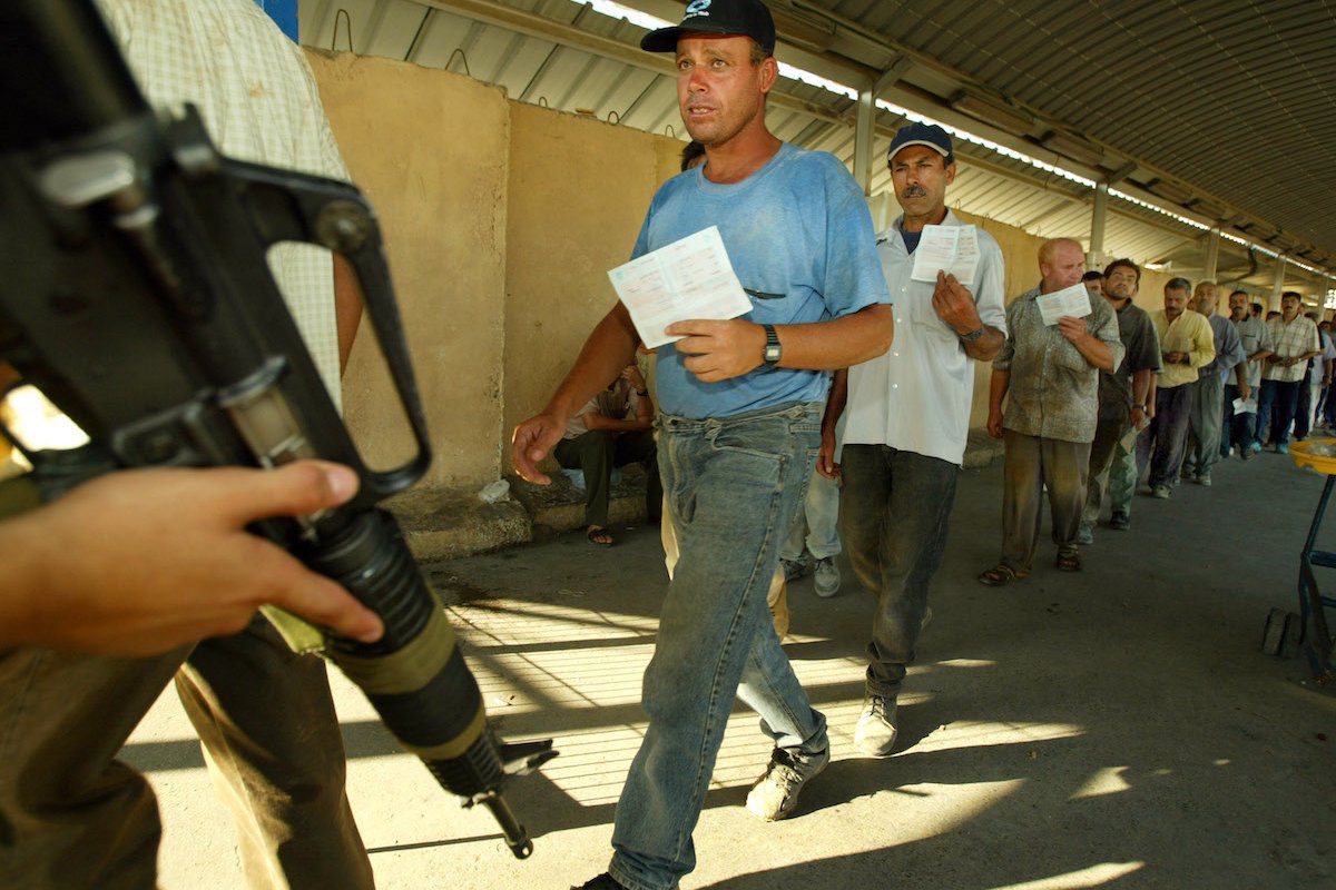 Trabalhadores palestinos cruzam de volta para a Faixa de Gaza vindos de Israel no posto de controle de Erez em 4 de setembro de 2003. [Paula Bronstein/ Getty Images]