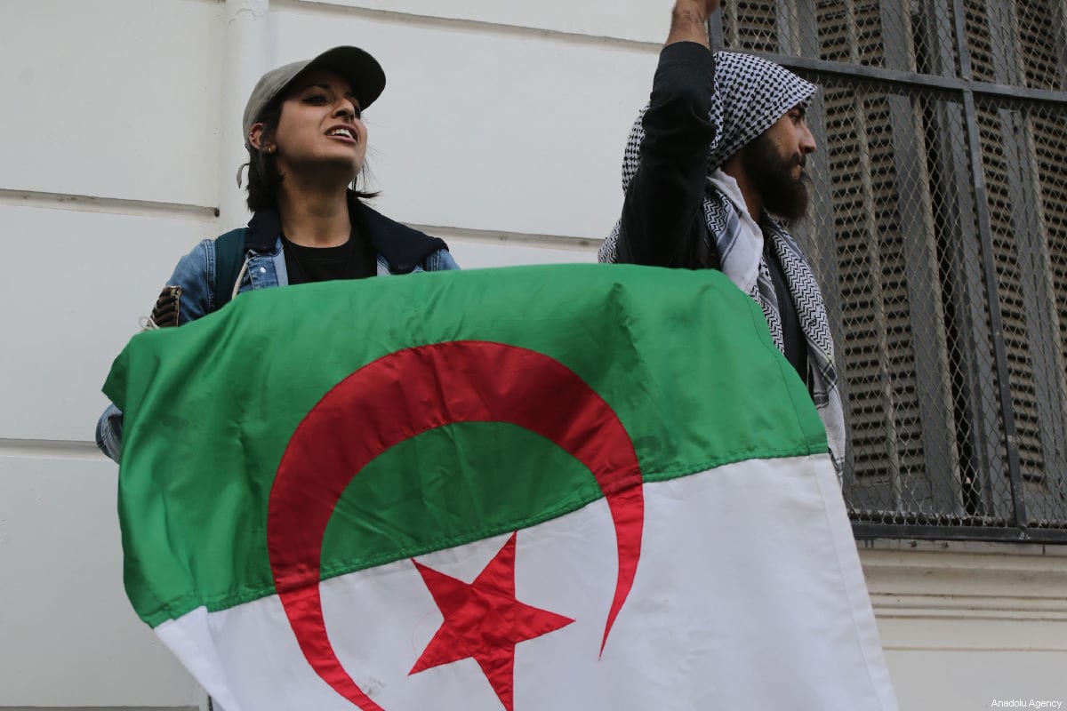 Manifestantes na Argélia seguram bandeira do país, em 26 de fevereiro de 2019 [Farouk Batiche/Agência Anadolu]

