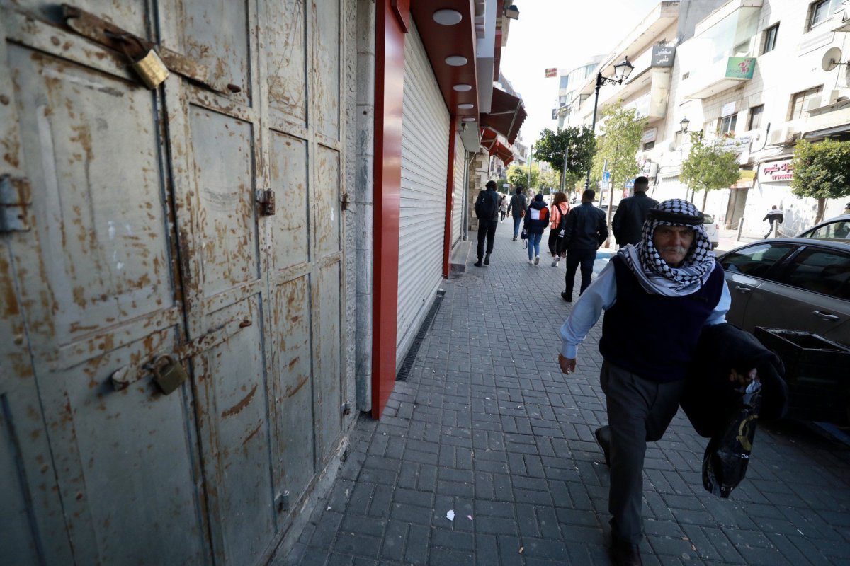 As pessoas passam pelas lojas fechadas devido à greve geral, realizada em certas cidades após 3 palestinos mortos pelas forças israelenses na cidade de Nablus, Cisjordânia, em Ramallah, Cisjordânia, em 9 de fevereiro de 2022. [Issam Rimawi - Anadolu Agência]
