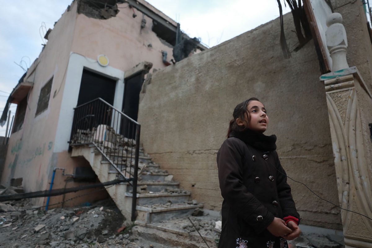 Menina em frente à casa do prisioneiro palestino Mahmoud Jaradat, demolida por forças israelenses, na aldeia de Silat al-Harisiyah, noroeste de Jenin, na Cisjordânia ocupada, 14 de fevereiro de 2022 [Issam Rimawi/Agência Anadolu]

