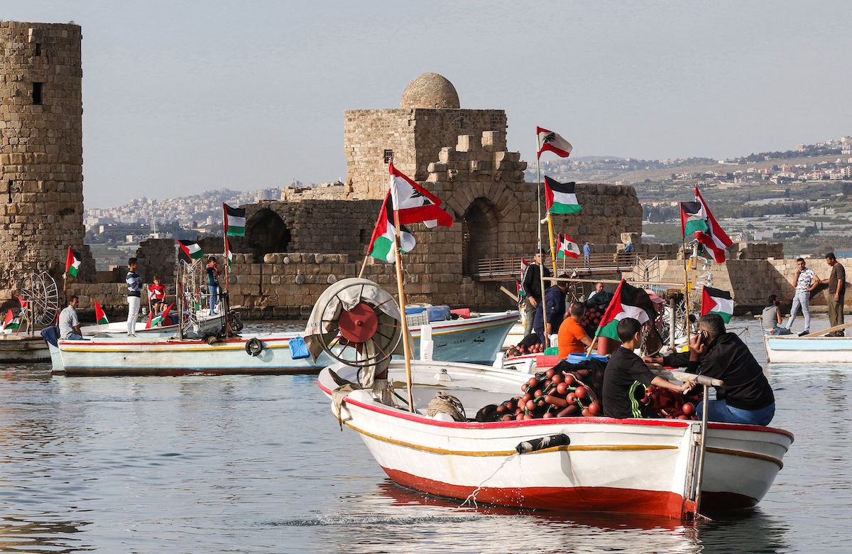 Refugiados palestinos e ativistas libaneses sentados em barcos de pesca participam de um evento marítimo de solidariedade palestina, em 6 de maio de 2021 [Mahmoud Zayyat/AFP via Getty Images]