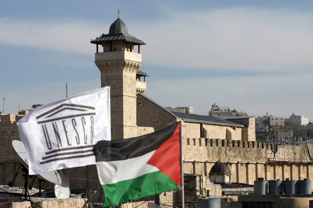 O Comitê de Reabilitação da Palestina levantou a bandeira da Unesco ao lado da bandeira nacional palestina em frente à Mesquita Ibrahimi de Hebron, em 13 de dezembro de 2011 [Hazem Bader/AFP via Getty Images]