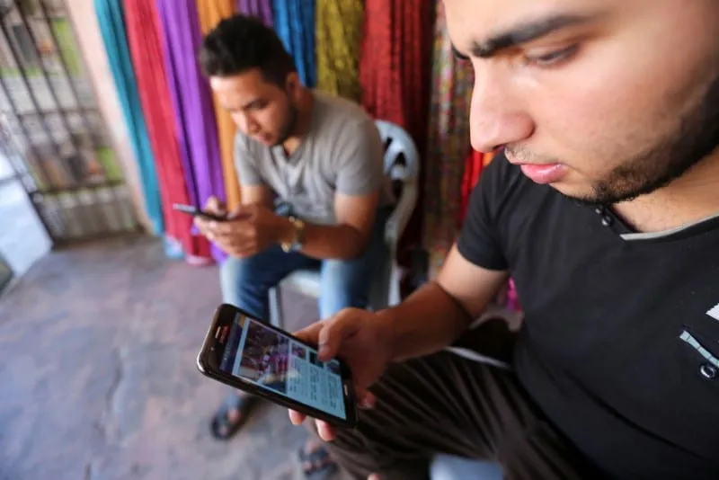Jovens palestinos em seus celulares [Ibraheem Abu Mustafa/Reuters]
