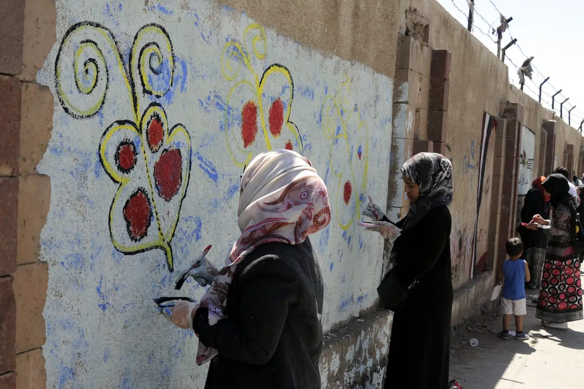 Mulheres iemenitas desenham pinturas na parede da Universidade de Sanaa para reagir à guerra em curso no país, Iêmen, em 15 de março de 2017 [Mohammed Hamoud/Agência Anadolu]
