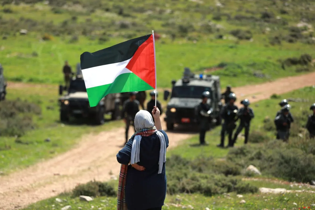 Uma mulher palestina segura uma bandeira nacional para protestar contra o controle de Israel sobre o território no Monte Al-Raysan e os assentamentos judaicos em Ramallah, Cisjordânia, em 22 de março de 2022 [Issam Rimawi/Agência Anadolu]
