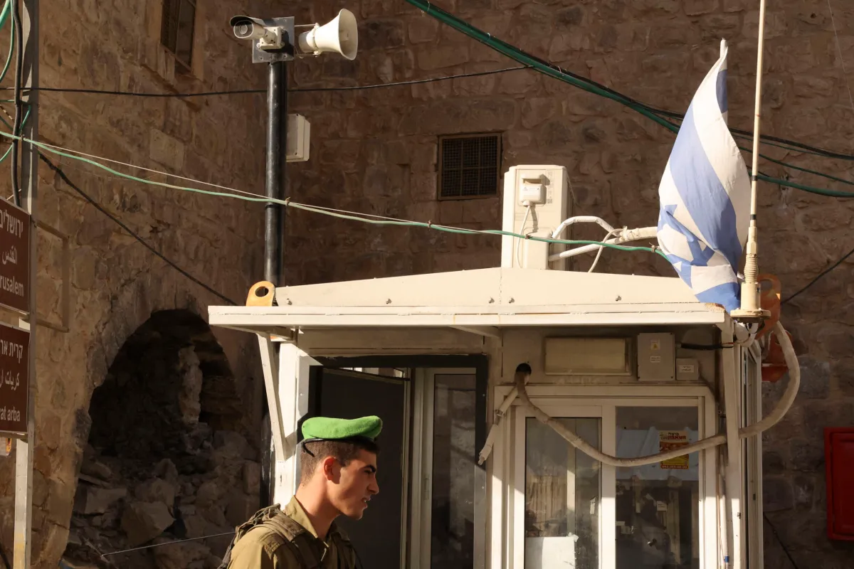 Um soldado israelense sob uma câmera de vigilância em um posto de controle na cidade palestina de Hebron, em 9 de novembro de 2021 [Hazem Bader/AFP via Getty Images]
