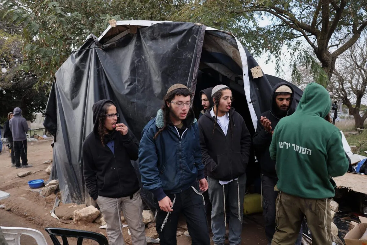 Colonos israelenses, estudantes da Homesh Yeshiva (escola religiosa), se reúnem em frente a uma tenda no antigo assentamento de Homesh, a oeste da cidade de Nablus, na Cisjordânia, em 30 de dezembro de 2021 [Menahem Kahana/AFP via Getty Images]
