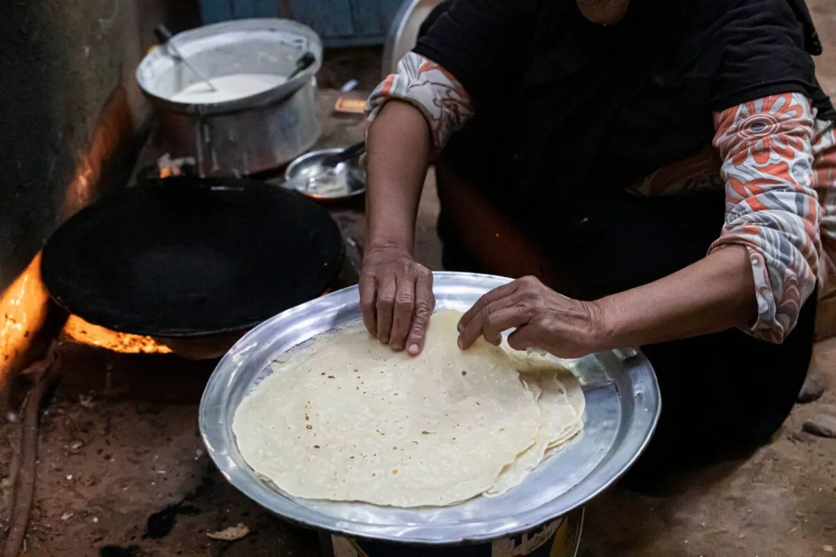 Mulher prepara pão para a família em sua casa na vila de Zerzara, na margem oeste do rio Nilo, na cidade de Aswan, no sul do Egito, em 26 de fevereiro de 2022 [Khaled Desouki/AFP via Getty Images]
