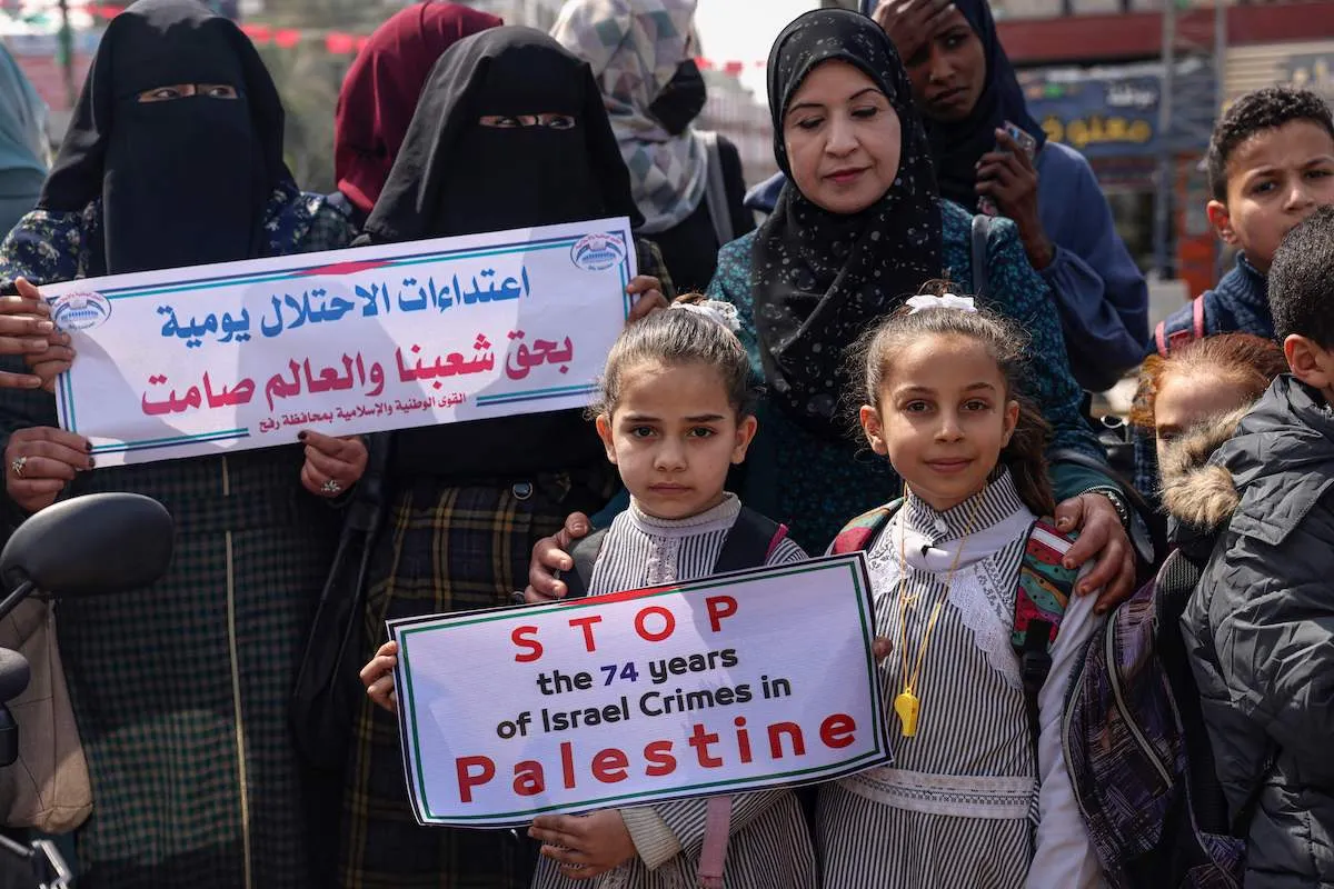 Palestinos levantam cartazes exigindo apoio internacional contra Israel semelhante ao demonstrado aos ucranianos contra a Rússia, durante um protestam no campo de refugiados de Rafah, no sul da Faixa de Gaza, em 7 de março de 2022. [Said Khatib/AFP via Getty Images]
