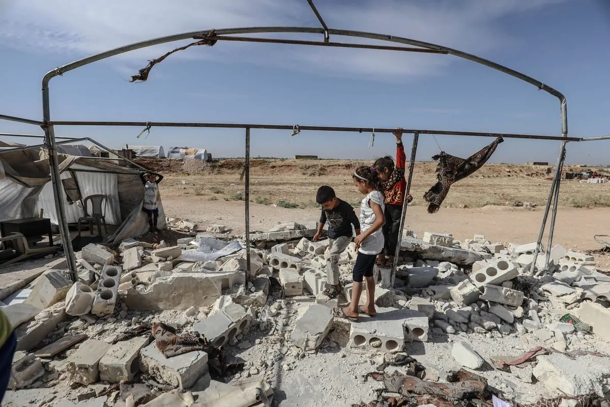 Crianças sírias entre os escombros de uma escola bombardeada por forças do regime de Bashar al-Assad, em Idlib, Síria, 11 de junho de 2021 [Izzeddin Kasim/Agência Anadolu]
