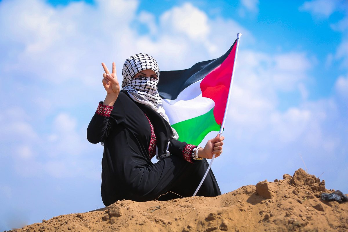 Mulher palestina com bandeira na faixa de Gaza sitiada [Hosny Sala/pixabay]