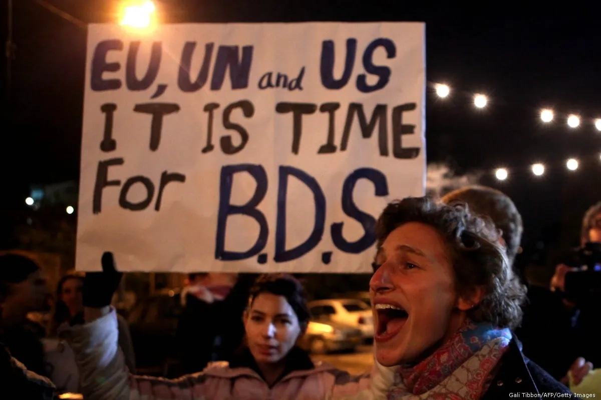 Manifestantes seguram um cartaz pedindo à comunidade internacional que apoie a campanha Boicote, Desinvestimento e Sanções (BDS) [Gali Tibbon/AFP/Getty Images]
