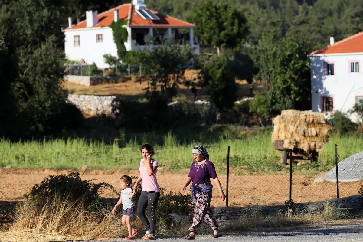 Pessoas retornam às suas casas no bairro de Feslegen, durante os incêndios florestais no distrito de Milas, em Mugla, Turquia, 7 de agosto de 2021 [Ömer Evren Atalay/Agência Anadolu]
