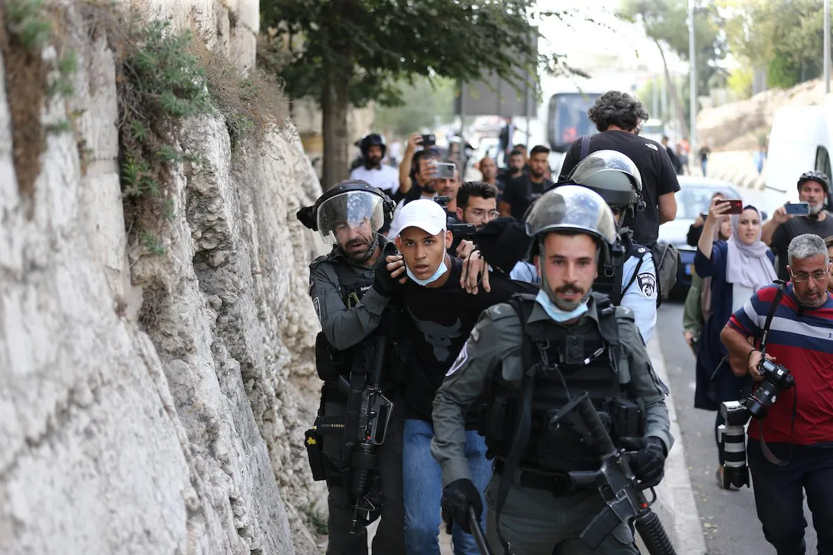 Forças de segurança israelenses prendem um palestino perto da entrada da mesquita de Al-Aqsa em Jerusalém [Mostafa Alkharouf/Agência Anadolu]
