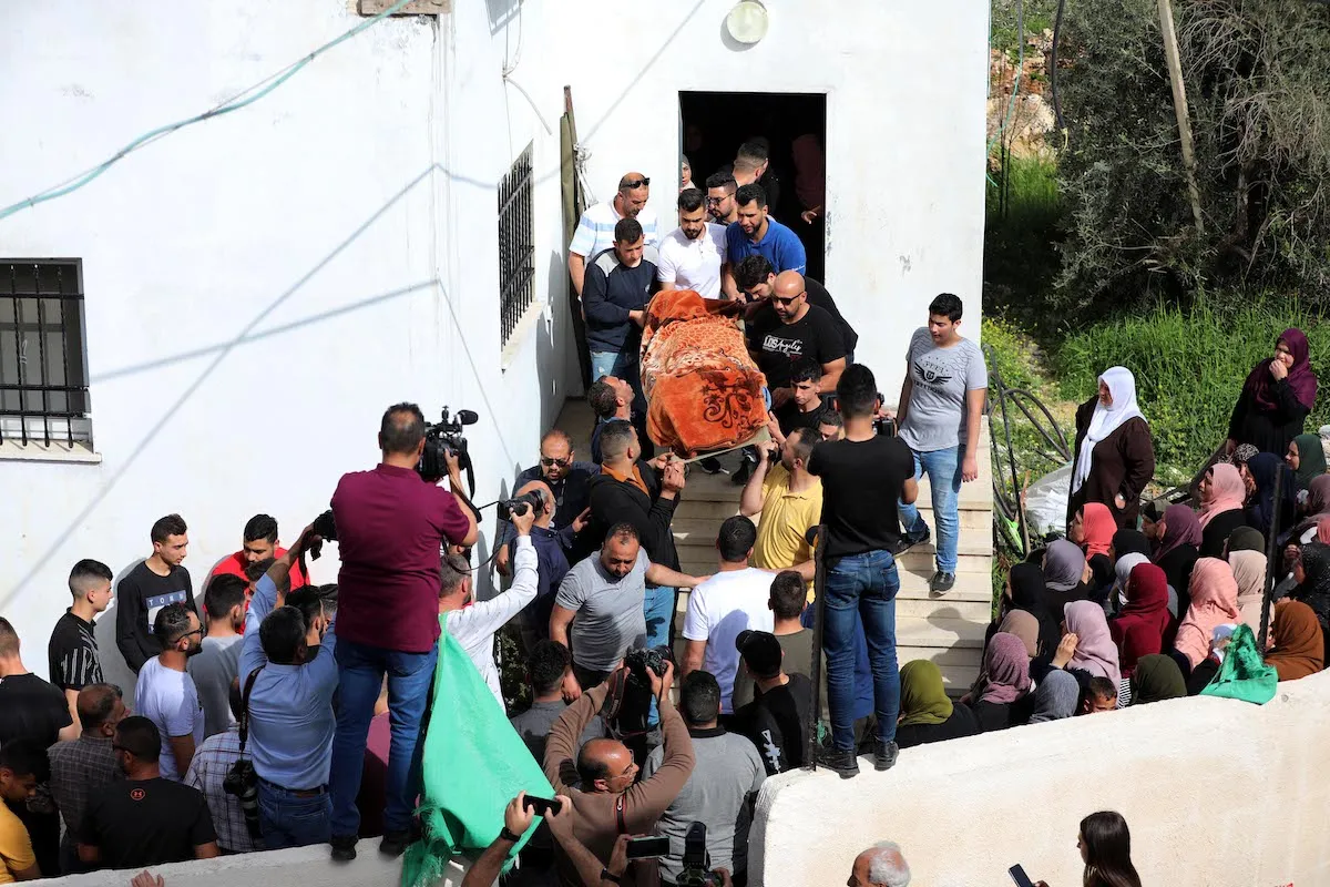 Palestinos carregam o corpo de Ghada Sabatin, 47, que morreu de seus ferimentos após ser baleada por soldados israelenses, durante seu funeral na vila de Husan, a oeste da cidade de Belém, na Cisjordânia ocupada, em 10 de abril de 2022 [Wisam Hashlamoun/Agência Anadolu]
