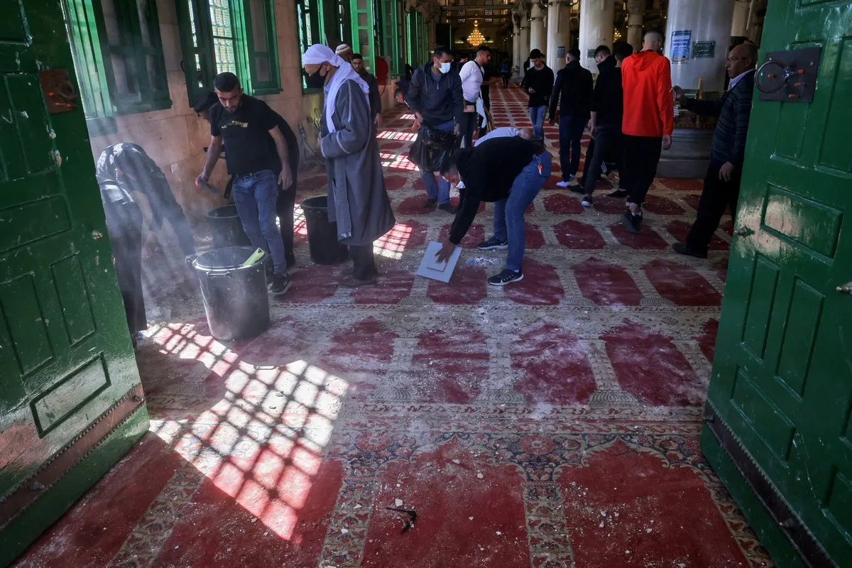 Palestinos limpam o assoalho da Mesquita de Al-Aqsa após ataques israelenses, em Jerusalém ocupada, 15 de abril de 2022 [Ahmad Gharabli/AFP via Getty Images]
