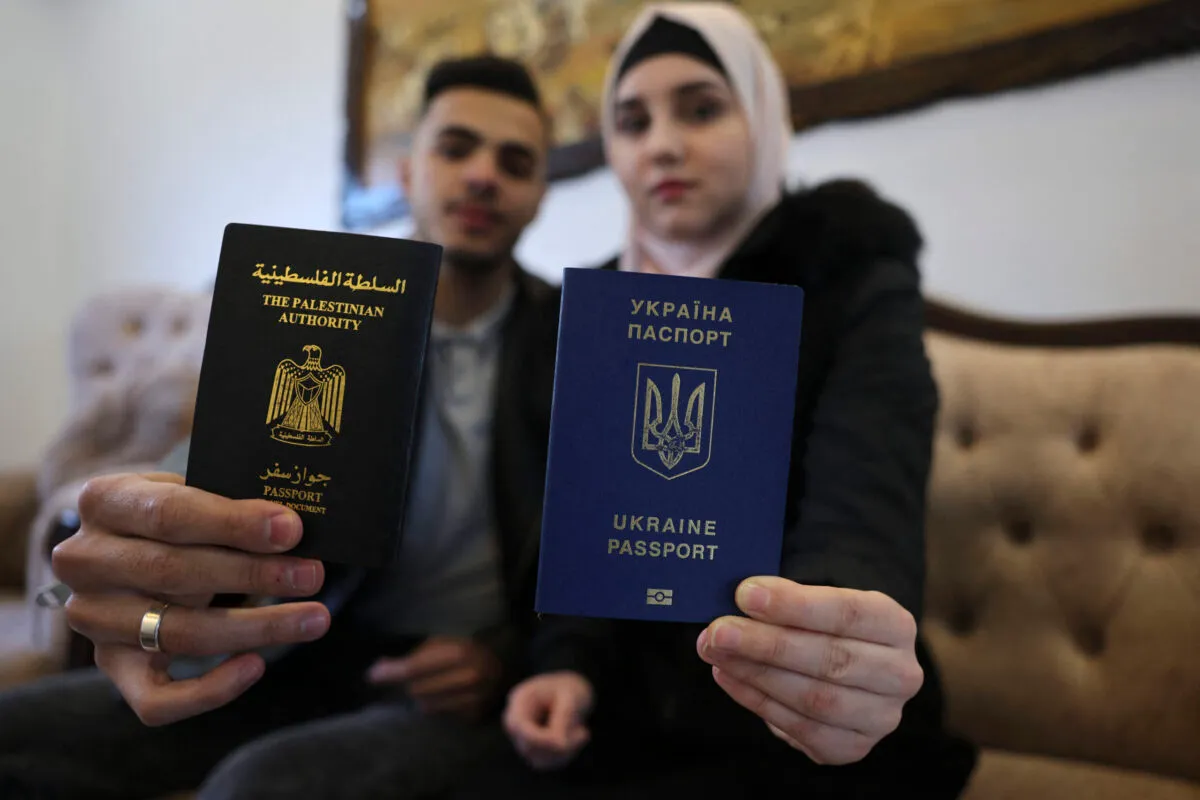  A ucraniana Viktoria Saidam (dir.) e seu marido palestino Ibrahim Saidam mostram seus passaportes na casa de sua família no campo de refugiados de Bureij, no centro da Faixa de Gaza, em 22 de março de 2022 [Said Khatib/AFP via Getty Images]
