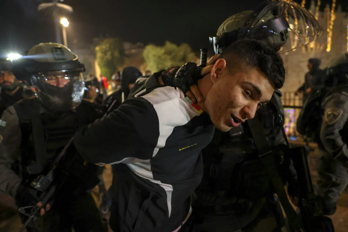 Forças de segurança israelenses detêm um jovem palestino durante confrontos em frente ao portão de Damasco que leva à cidade velha de Jerusalém, em 6 de abril de 2022 [Ahmad Gharabli/AFP via Getty Images]

