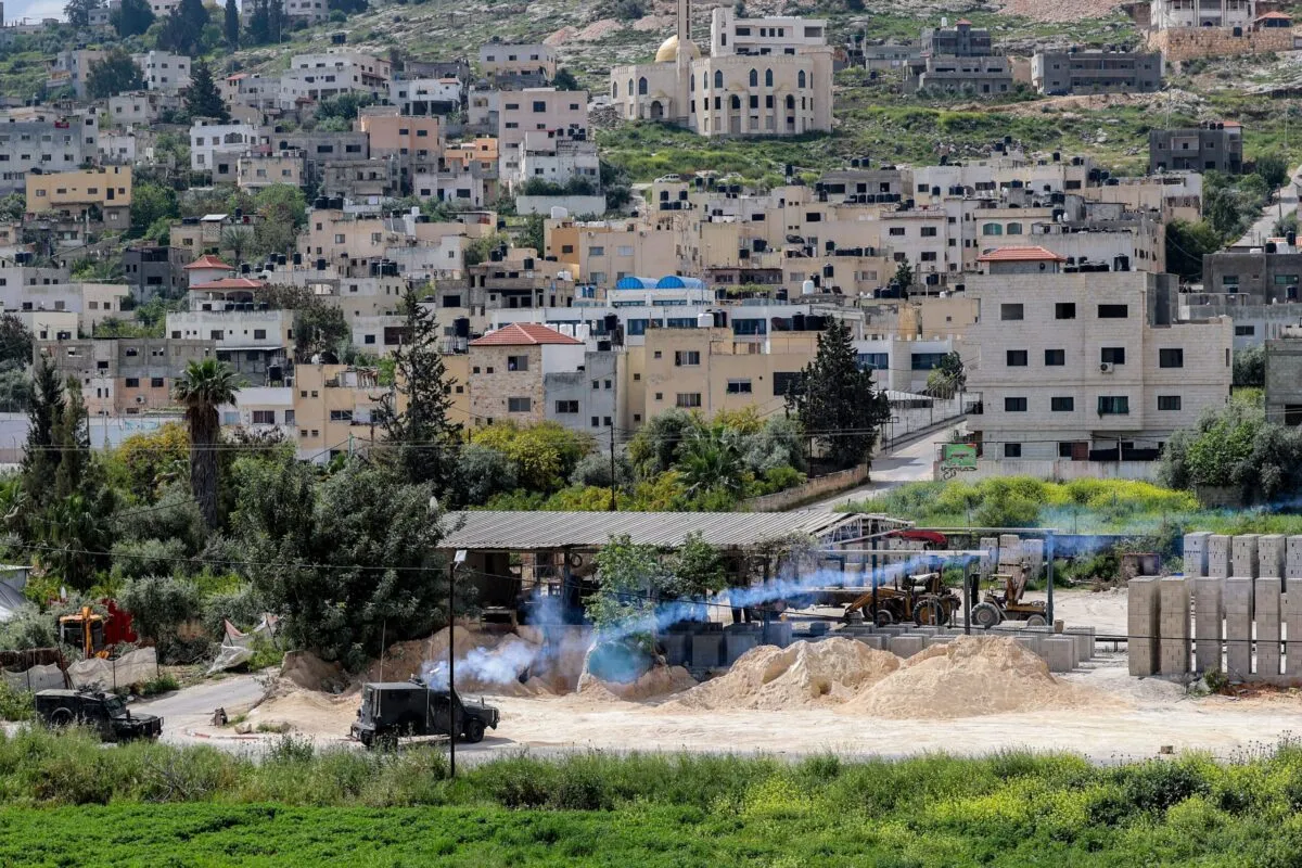 Vasilhas de gás lacrimogêneo são disparadas de um veículo militar israelense perto do campo de refugiados palestinos de Jenin, na Cisjordânia ocupada, em 9 de abril de 2022 [Jaafar Ashtiyeh/AFP via Getty Images]