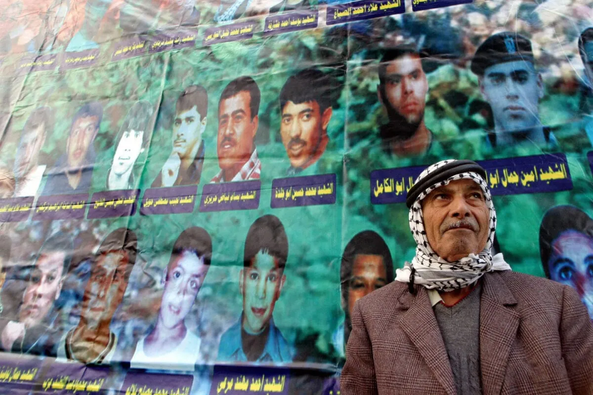 Cartazes relembram as vítimas do massacre no campo de refugiados em Jenin, em 2002, conduzido por soldados da ocupação israelense [Saif Dahlah/AFP via Getty Images]
