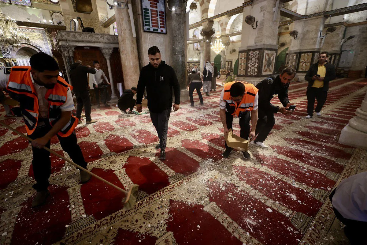 Palestinos limpam o assoalho da Mesquita de Al-Aqsa após ataques israelenses, em Jerusalém ocupada, 15 de abril de 2022 [Ahmad Gharabli/AFP via Getty Images]
