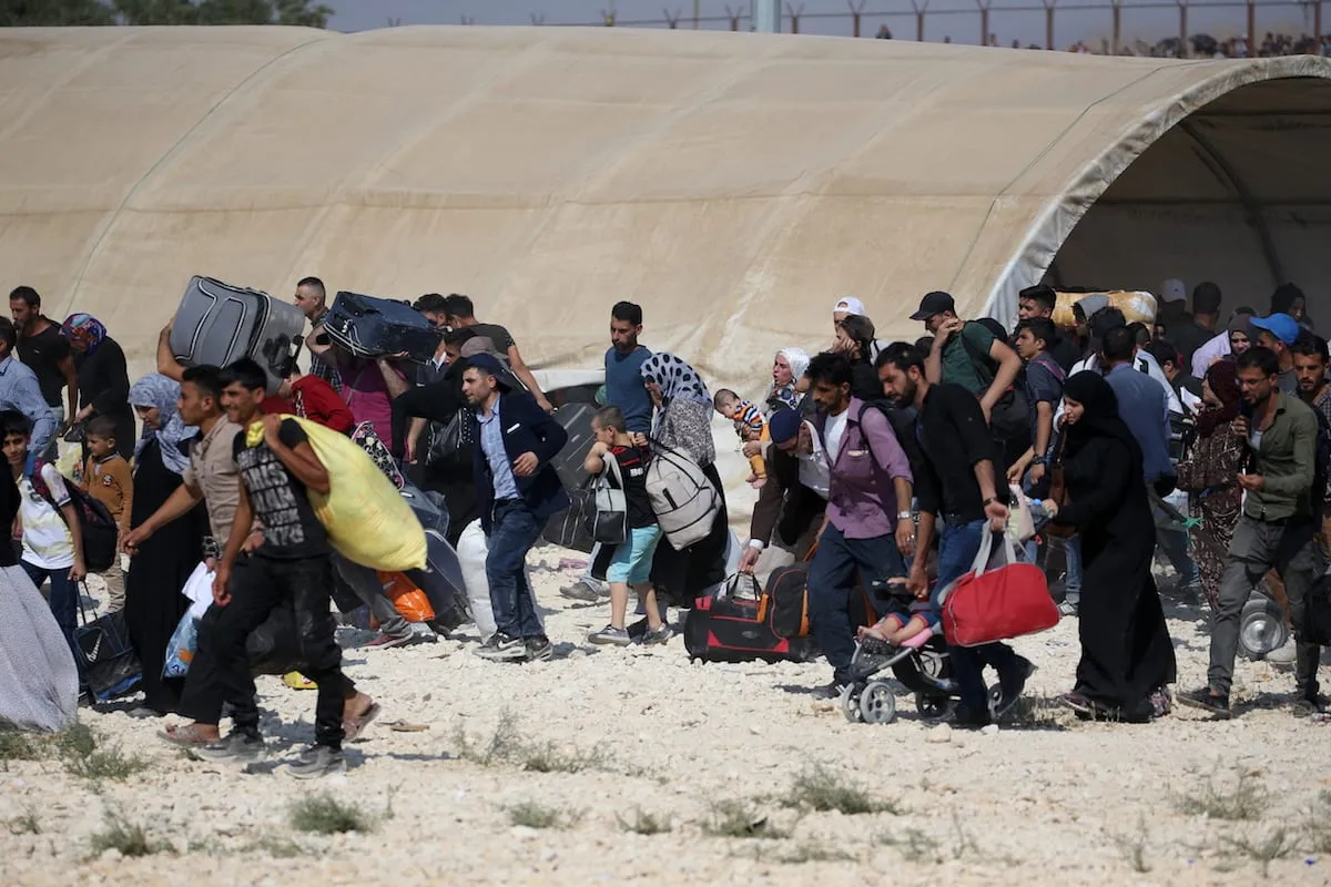 Refugiados sírios com seus pertences passam pelo portão de fronteira de Oncupinar para chegar às suas cidades natais antes do Eid al-Adha em Kilis, Turquia, em 29 de agosto de 2017 [Ensar Özdemir/Agência Anadolu]

