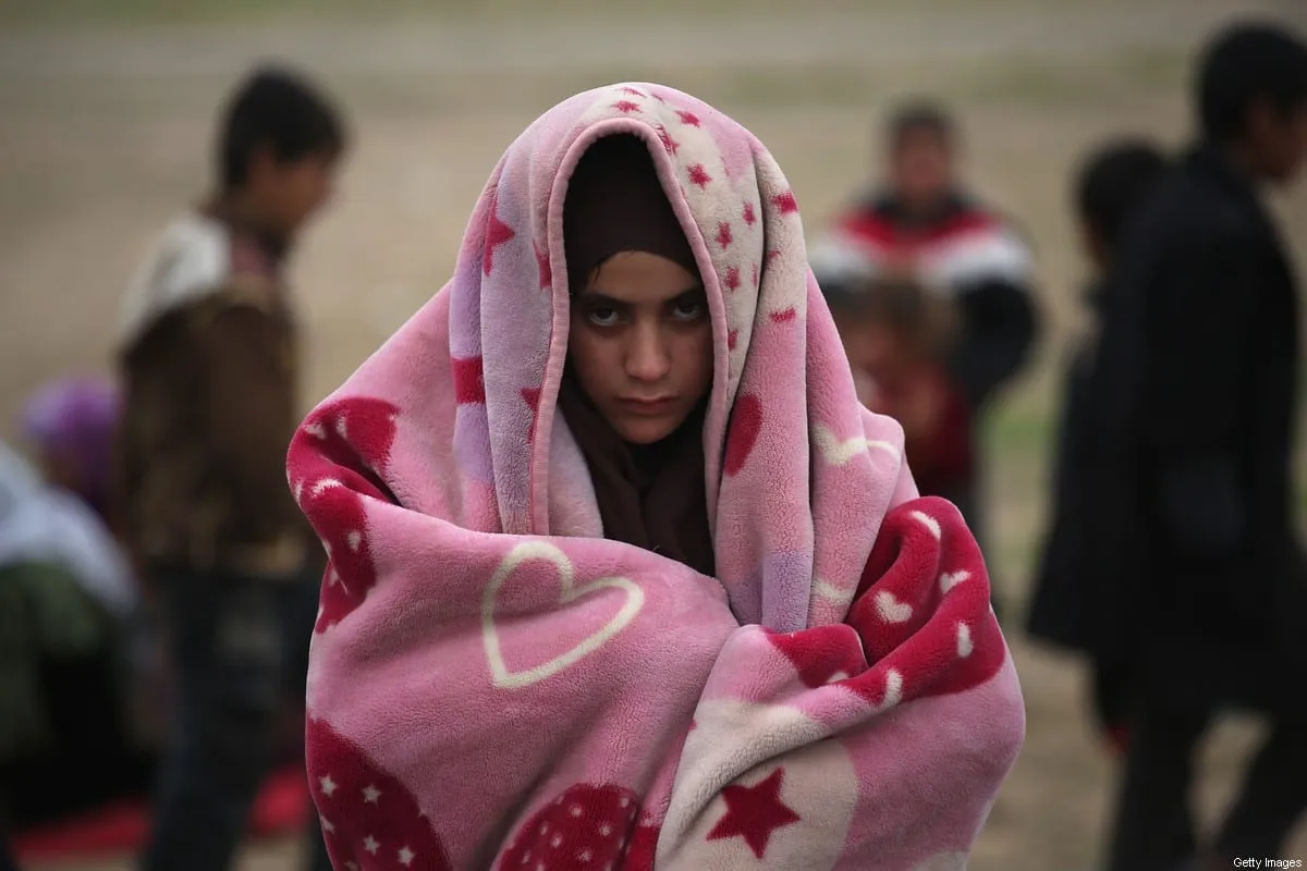 Uma menina se protege contra o frio enquanto fugia de uma vila da linha de frente controlada pelo Daesh, em 16 de novembro de 2015 para Sinjar, Iraque [John Moore/Getty Images]
