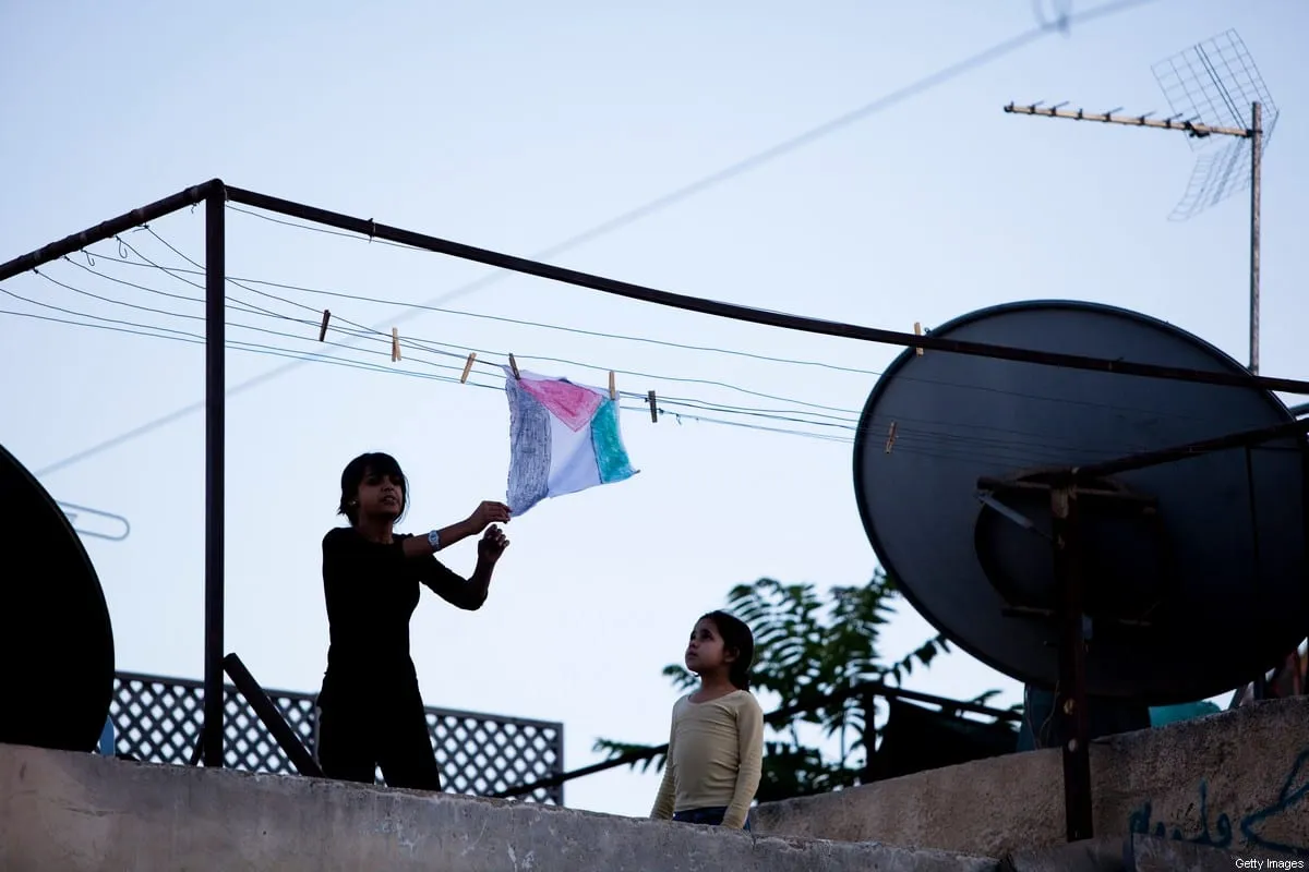 Crianças penduram o desenho de uma bandeira no telhado durante marcha israelense em Jerusalém ocupada, 12 de maio de 2010 [Uriel Sinai/Getty Images]
