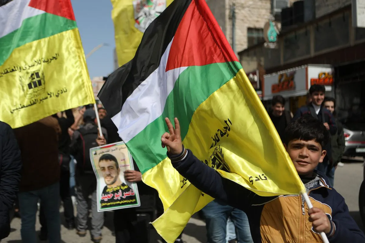 Manifestantes palestinos segurando faixas se reúnem durante uma manifestação para apoiar palestinos em prisões israelenses em 1º de março de 2022 [Mamoun Wazwaz/Agência Anadolu]
