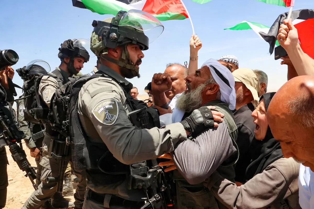 Um homem idoso palestino enfrenta um membro das forças israelenses enquanto ativistas israelenses, estrangeiros e palestinos se manifestam contra o despejo de aldeias palestinas para dar lugar a uma zona de treinamento militar israelense, nas colinas do sul de Yatta, ao sul da cidade de Hebron, na Cisjordânia, em 20 de maio de 2022. (Hazem Bader/AFP via Getty Images)
