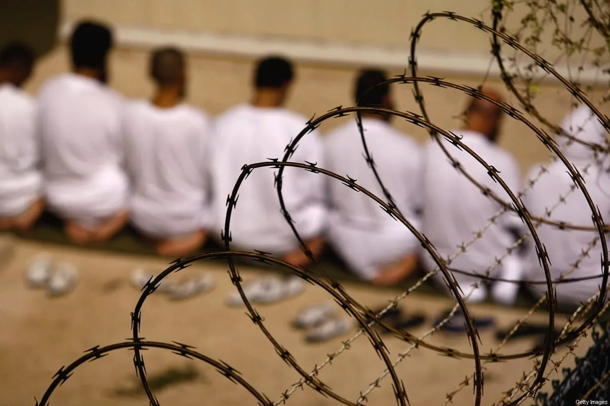 Grupo de prisioneiros ajoelhados na Baía de Guantánamo, em Cuba, 28 de outubro de 2009 [John Moore/Getty Images]
