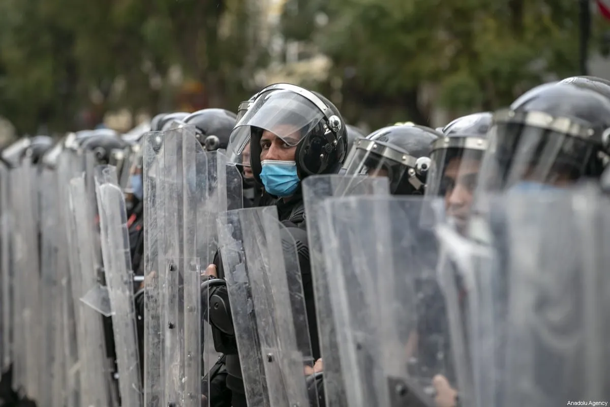 Policiais bloqueiam a estrada enquanto as pessoas realizam uma manifestação exigindo a libertação de detidos presos em um protesto realizado contra o bloqueio da pandemia de coronavírus (Covid-19), na rua Habib Burgiba, em Túnis, Tunísia, em 23 de janeiro de 2021. [Yassine Gaidi - Agência Anadolu ]
