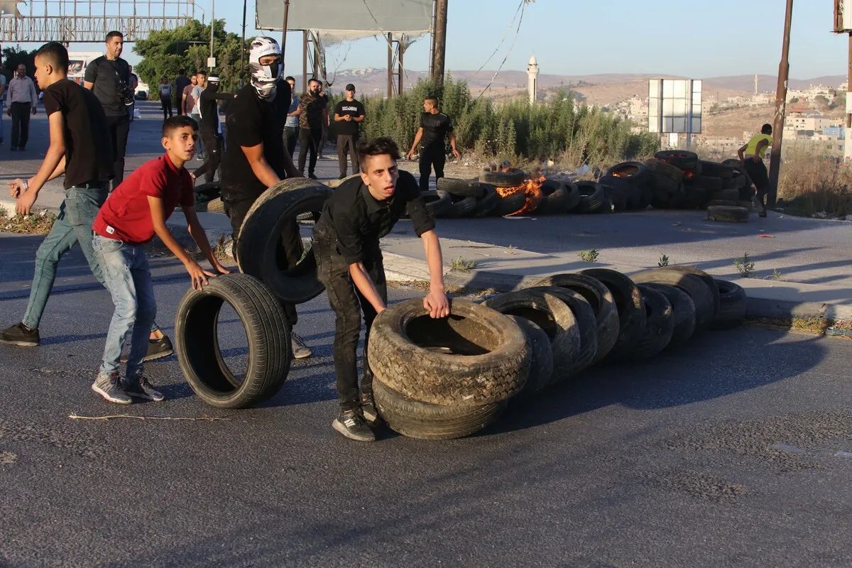 Palestinos montam barricada em protesto contra o assassinato de quatro palestinos em uma nova invasão militar israelense ao campo de refugiados de Jenin, na Cisjordânia ocupada, 28 de setembro de 2022 [Nedal Eshtayah/Agência Anadolu]
