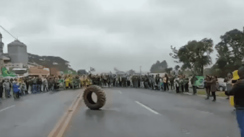 Bolsonaristas cantam hino nacional para pneu [Reprodução/Redes Sociais via O Povo]
