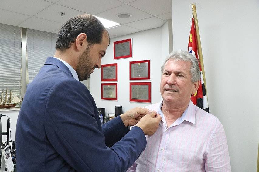 Ahmad Alzoubi, do FLP, entrega a insígnia da Liga de Parlamentares por Al-Quds, um  broche que é usado preso à camisa, ao deputado Enio Tatto [Assessoria Parlamentar/ALESP]