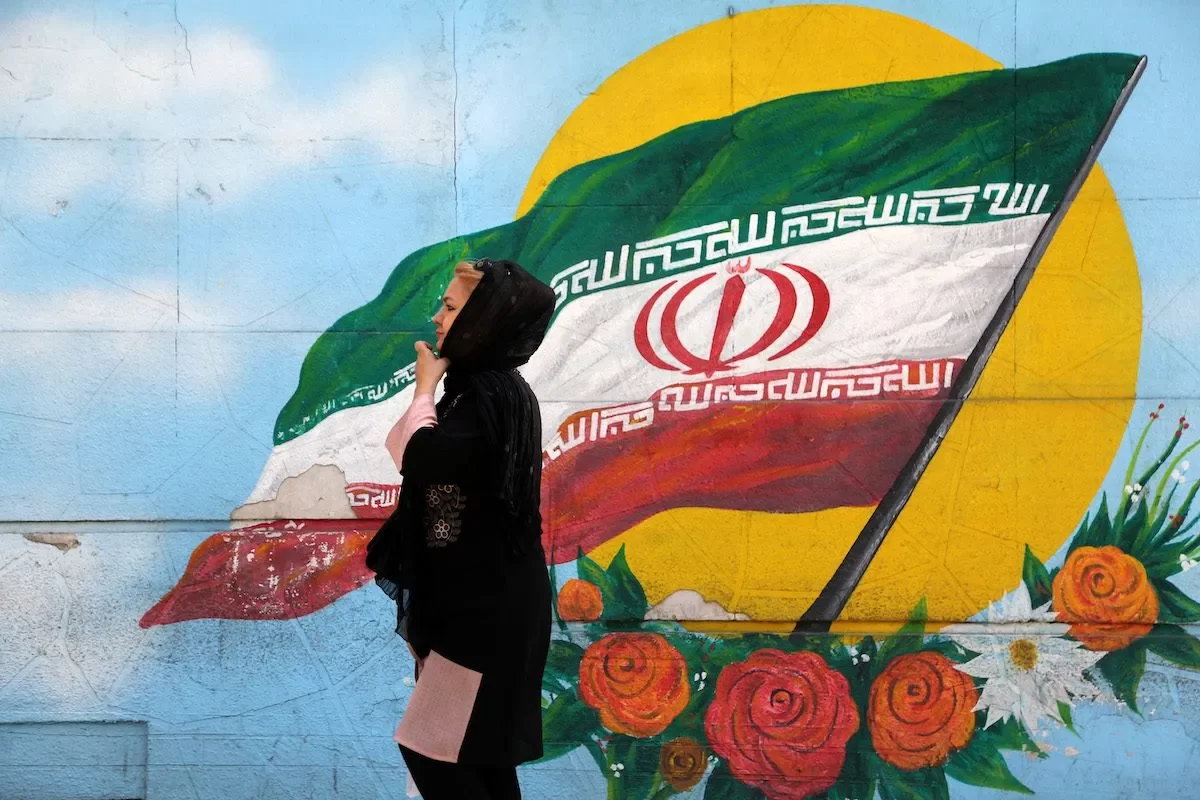 Mulher caminha em frente a um mural com a bandeira iraniana, em Teerã, 22 de setembro de 2022 [Fatemeh Bahrami/Agência Anadolu]