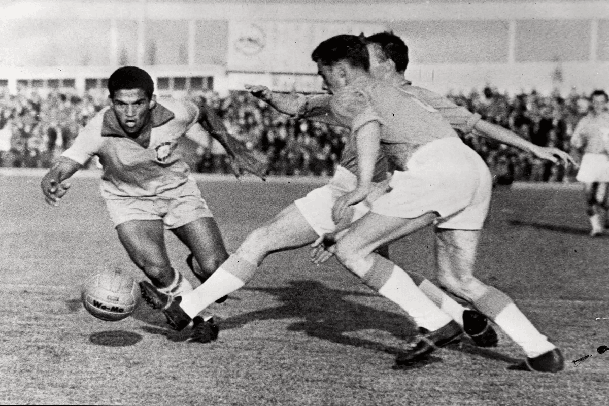 Manoel Francisco dos Santos (Garrincha) dribla adversários durante partida da Copa do Mundo FIFA de Futebol de 1962, no Chile [El Gráfico/Domínio Público]
