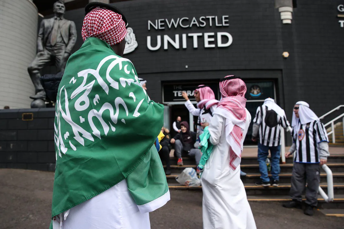 Torcedores do Newcastle United vestem bandeira e lenço tradicional saudita durante jogo pela Premier League contra o clube Tottenham Hotspur, em Londres, 16 de outubro de 2021 [Robbie Jay Barratt/AMA/Getty Images]
