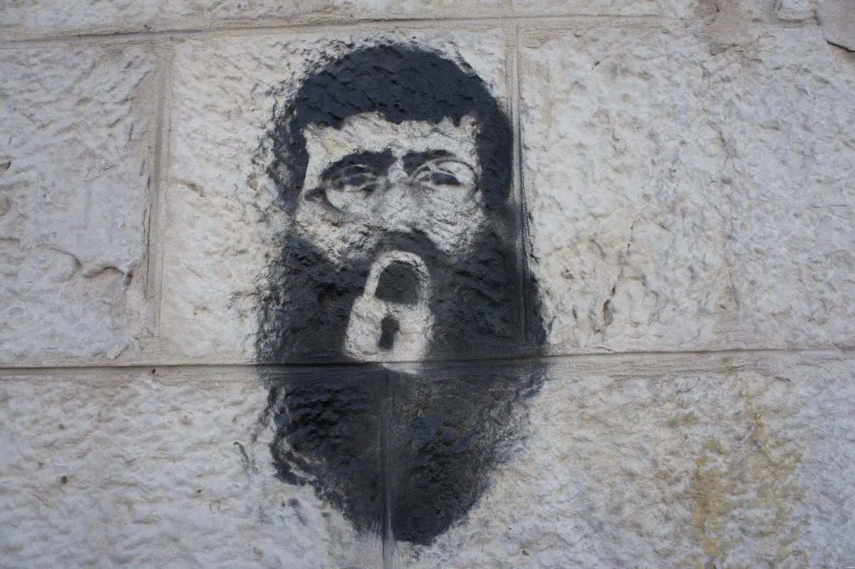 Grafite do prisioneiro palestino Khader Adnan em uma parede da praça Manara, em Ramallah, Cisjordânia ocupada, em 23 de fevereiro de 2012 [Wikipedia]
