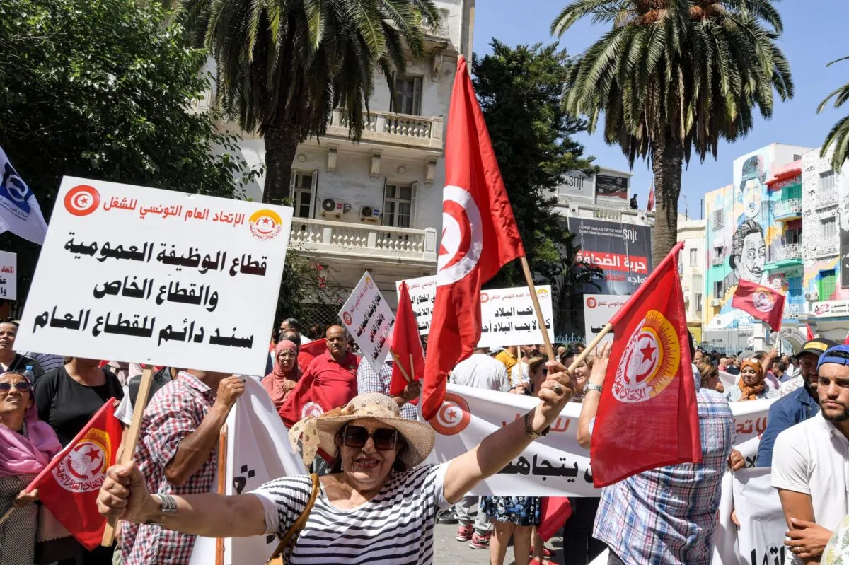 Apoiadores da União Geral dos Trabalhadores da Tunísia (UGTT) se reúnem com bandeiras nacionais durante uma manifestação em frente à sua sede na capital Tunis sua sede na capital Tunis [Fethi Belaid/AFP Getty Images]
