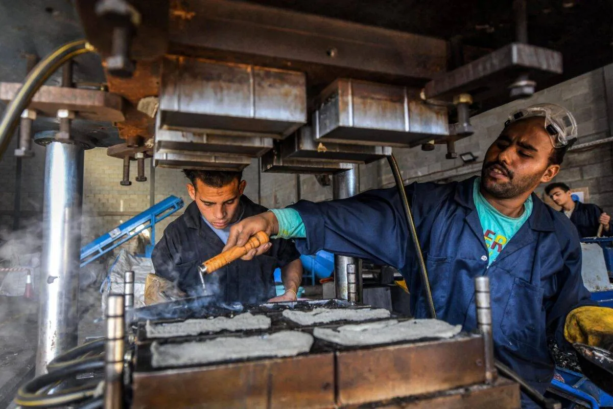 Um trabalhador prepara moldes de resíduos de plástico em uma oficina da empresa iniciante 'TileGreen', onde o material é reciclado e transformado em ladrilhos ecológicos no Ashir min Ramadan, no Egito, em 8 de dezembro de 2022 [Ahmed Hasan/AFP via Getty Images] 
