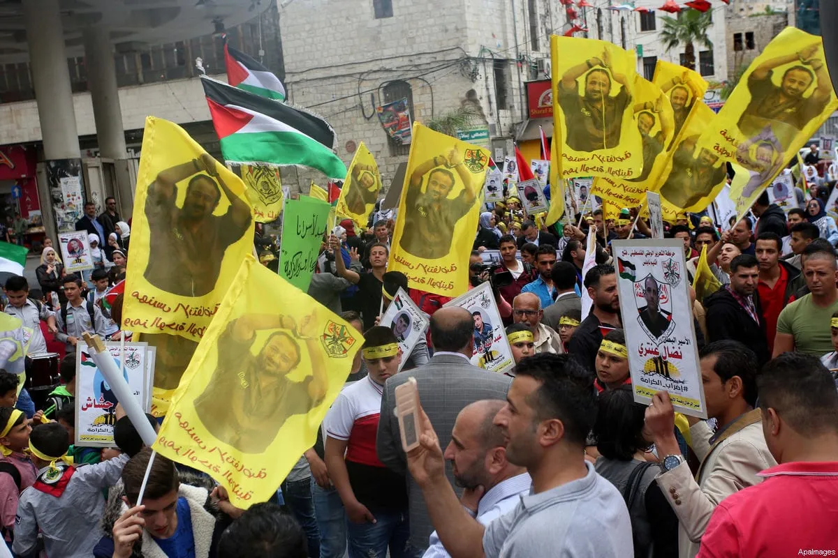 Manifestantes palestinos agitam bandeiras com o retrato do líder popular preso Marwan Barghouti em solidariedade aos prisioneiros palestinos em greve de fome nas prisões israelenses, na Cisjordânia, em 23 de abril de 2017 [Ayman Ameen / ApaImages]
