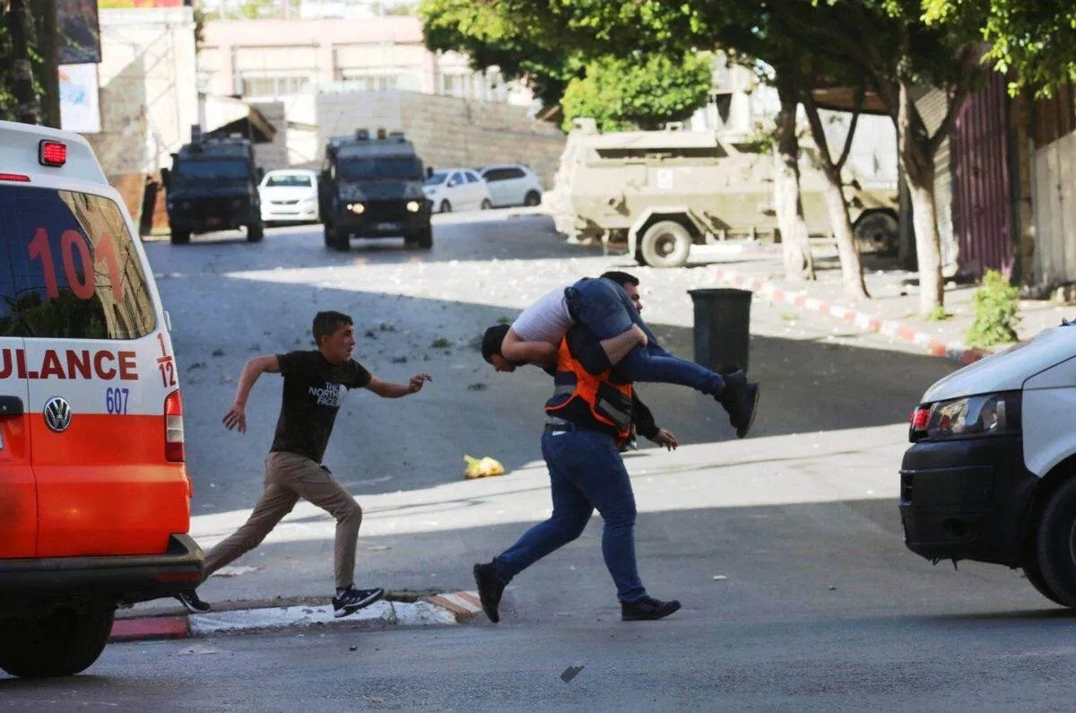 Paramédico carrega palestino ferido após invasão do exército israelense em Nablus, Cisjordânia ocupada, em 4 de maio de 2023 [Nedal Eshtayah/Agência Anadolu]
