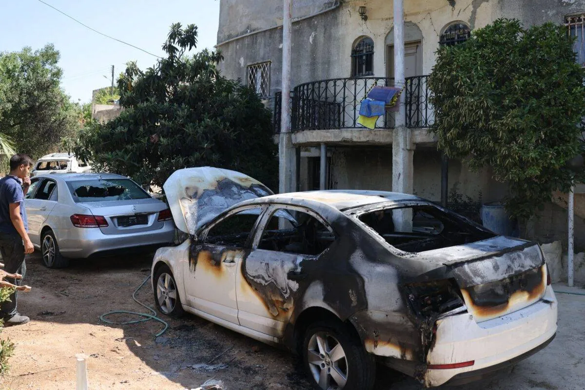 Homem verifica um carro supostamente incendiado por colonos israelenses, na área de al-Lubban al-Sharqiya, na Cisjordânia ocupada, em 21 de junho de 2023 [Ahmad Gharabli/AFP via Getty Images]
