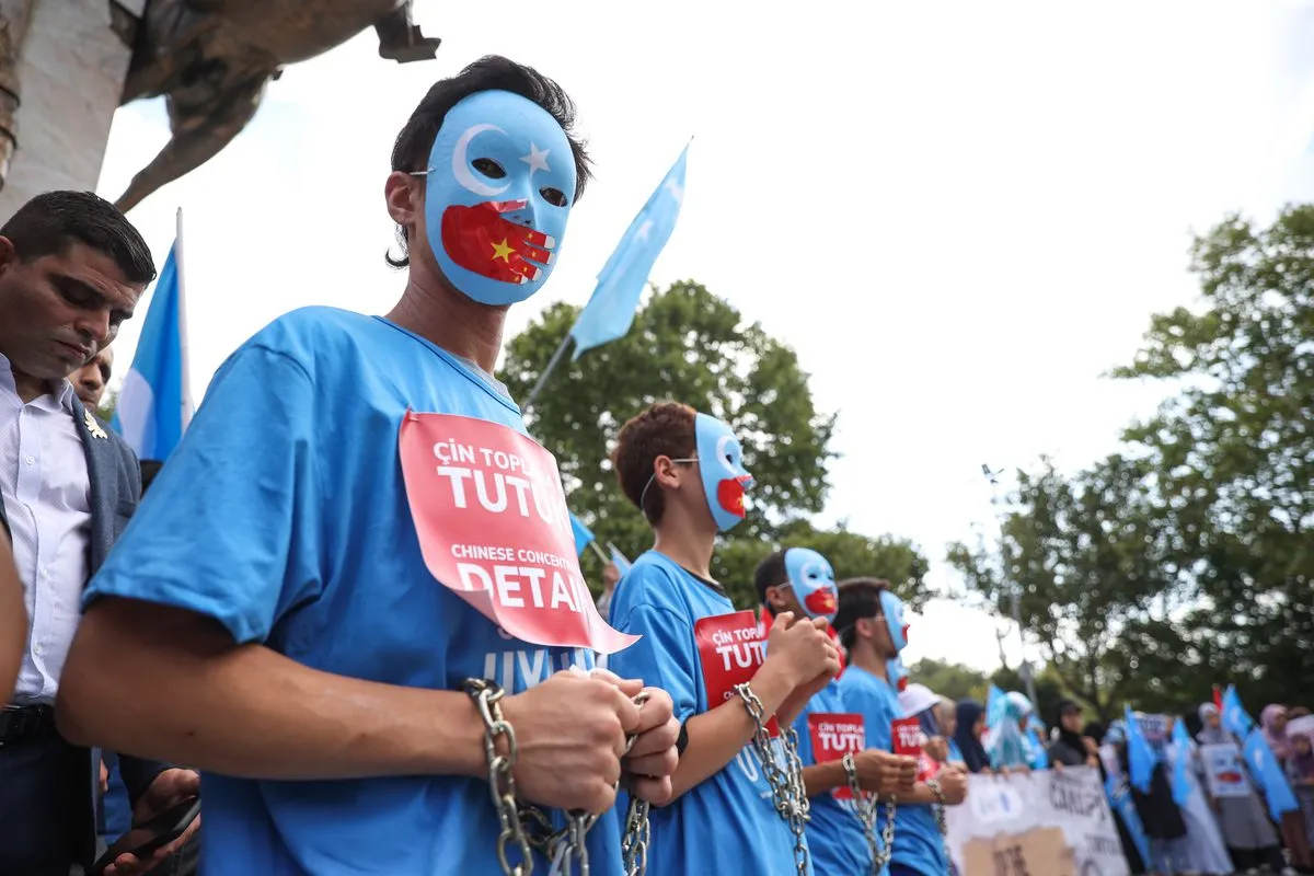 Manifestantes com correntes nas mãos e nos pés fazem um protesto como parte da campanha mundial "Stop Genocide Now" para chamar a atenção para as políticas da China em relação à Região Autônoma Uigur de Xinjiang, em Fatih, Istambul, Turquia, em 31 de julho de 2022 [Muhammed Enes Yıldırım/Agência Anadolu]
