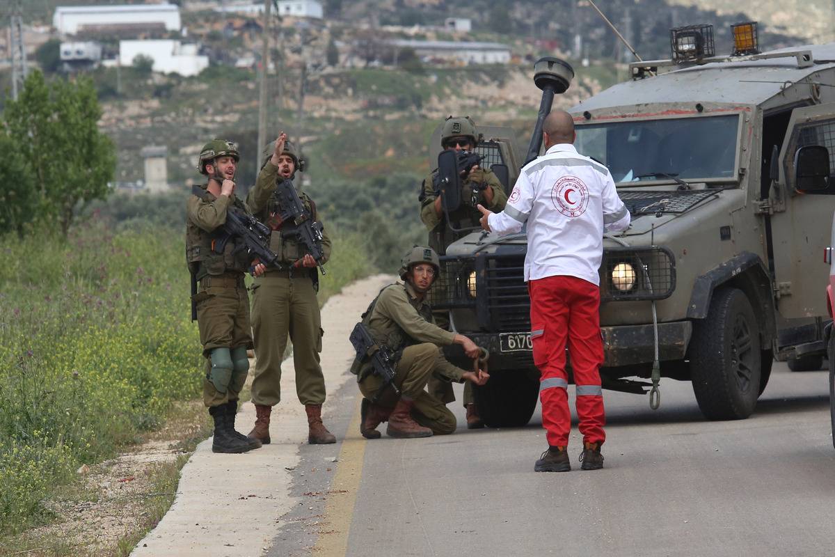 Soldados israelenses impedem paramédicos de resgatar dois palestinos baleados em Nablus, na Cisjordânia ocupada, em 11 de abril de 2023 [Nedal Eshtayah/Agência Anadolu]
