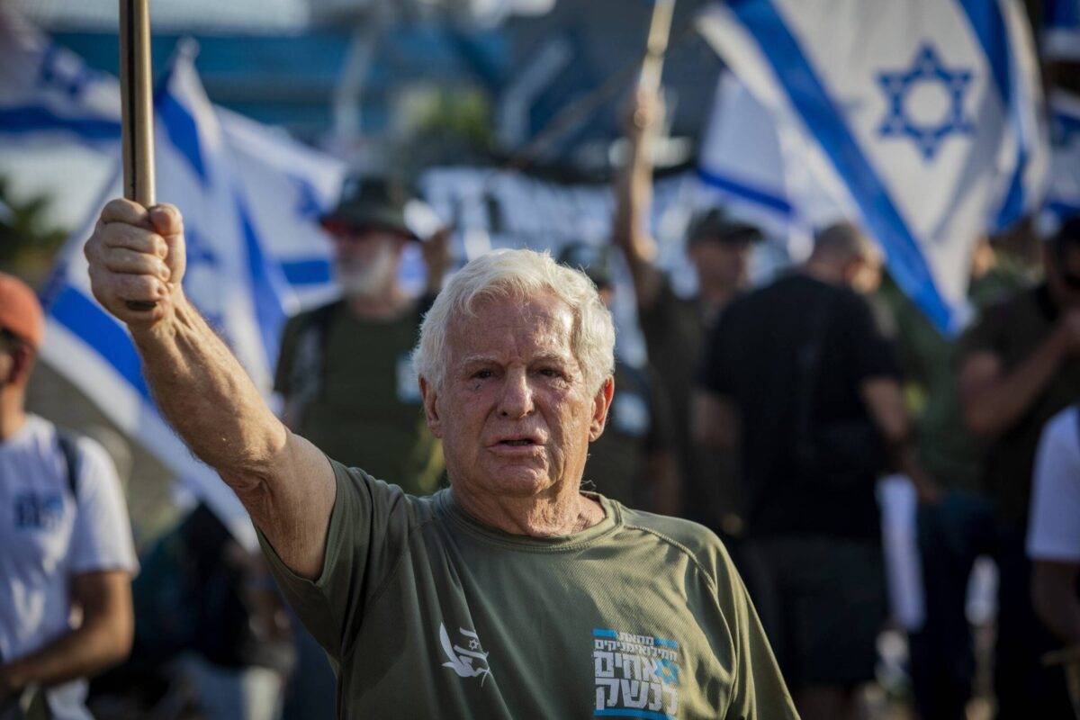 O general da reserva Amiram Levin segura a bandeira israelense durante a manifestação do lado de fora do porto marítimo de Haifa [Eyal Warshavsky/SOPA Images/LightRocket via Getty Images]
