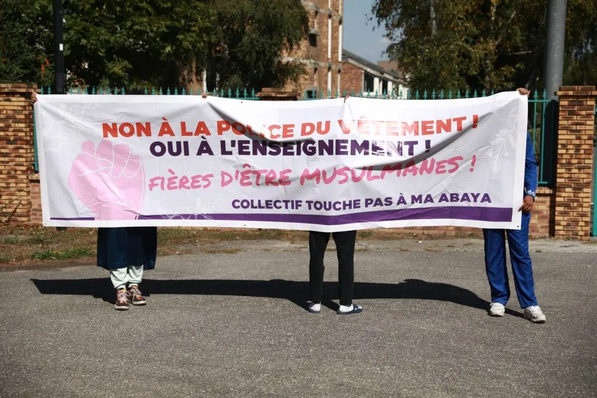Manifestantes seguram uma faixa enquanto protestam contra a interdição de Abaya em frente à escola Lycee La Plaine de Neauphle em Trappes, França, em 8 de setembro de 2023 [Mohamad Salaheldin Abdelg Alsayed/Agência Anadolu]
