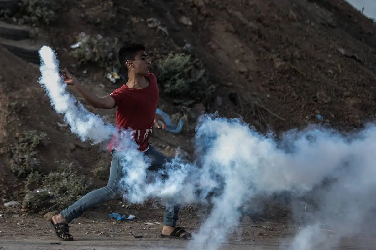 Palestino devolve bomba de gás lacrimogêneo disparada por forças israelenses na região de Khan Yunis, na Faixa de Gaza, em 20 de setembro de 2023 [Ali Jadallah/Agência Anadolu]
