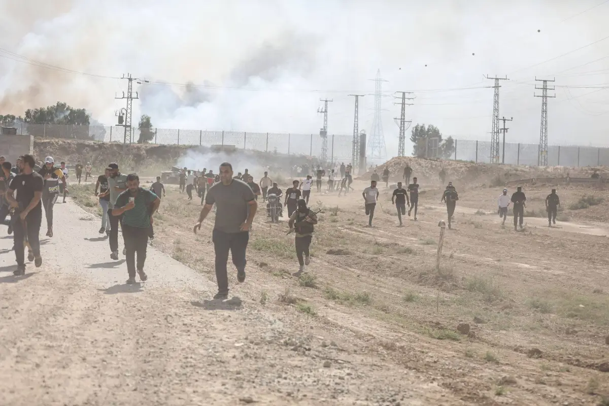 Palestinos fogem sob disparos de Israel na cerca de Gaza, em 7 de outubro de 2023 [Mustafa Hassona/Agência Anadolu]
